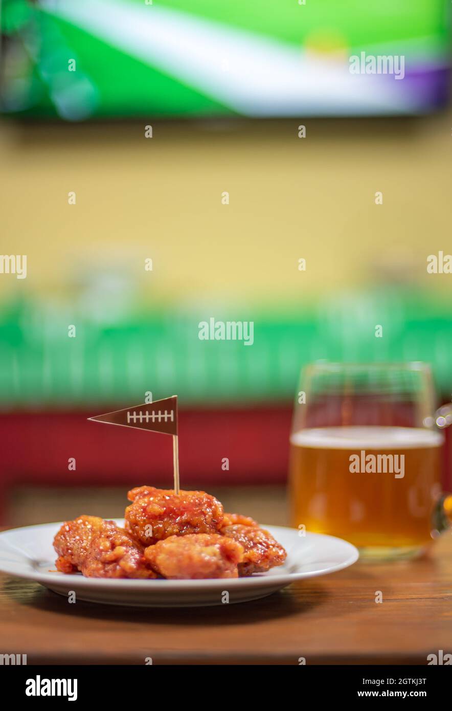 Plato de alitas de pollo deshuesadas a la barbacoa y taza de cerveza grande  de cristal lista para el partido de fútbol Fotografía de stock - Alamy