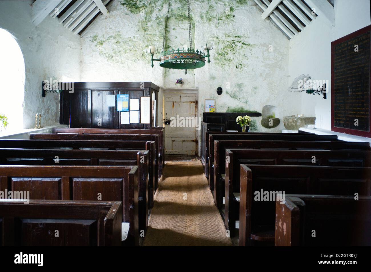 Interior de la pequeña capilla de San Runius cerca de Colby, Isla de Man mirando hacia la entrada, no hay suministro eléctrico, así que toda la iluminación es por candl Foto de stock