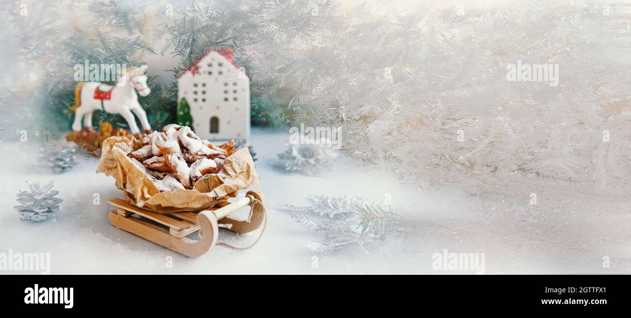 Decoración navideña con trineo de madera antiguo. Galletas caseras recién horneadas en la forma de un árbol de Navidad con decoraciones coloridas o. Foto de stock