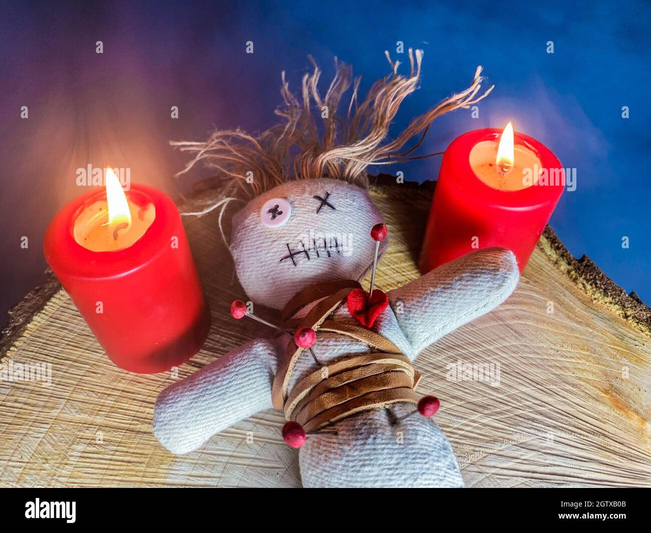Una muñeca Voodoo y dos velas rojas están en un corte de árbol Fotografía  de stock - Alamy
