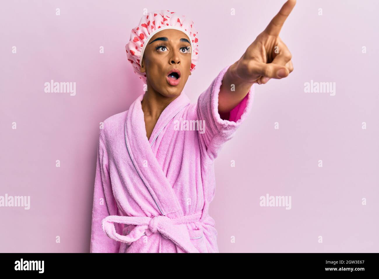 Hombre hispano con gorro de toalla de ducha y albornoz apuntando con mano  de dedo a cara y nariz, alegre y sonriente. Concepto de belleza Fotografía  de stock - Alamy