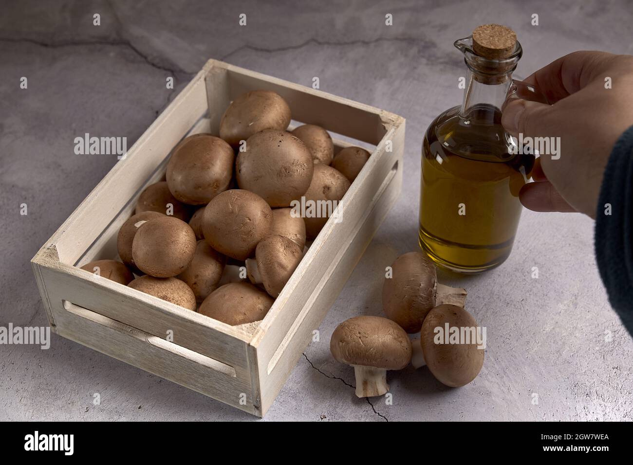 Grupo de setas Portobello en una caja de madera junto a un tarro de aceite Foto de stock