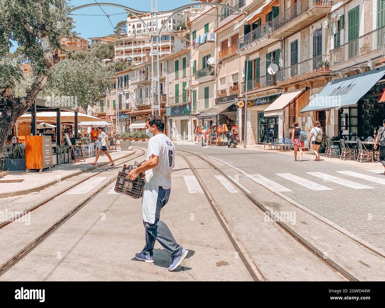 Camarero que lleva una maleta al otro lado de la calle con vías de tranvía Foto de stock