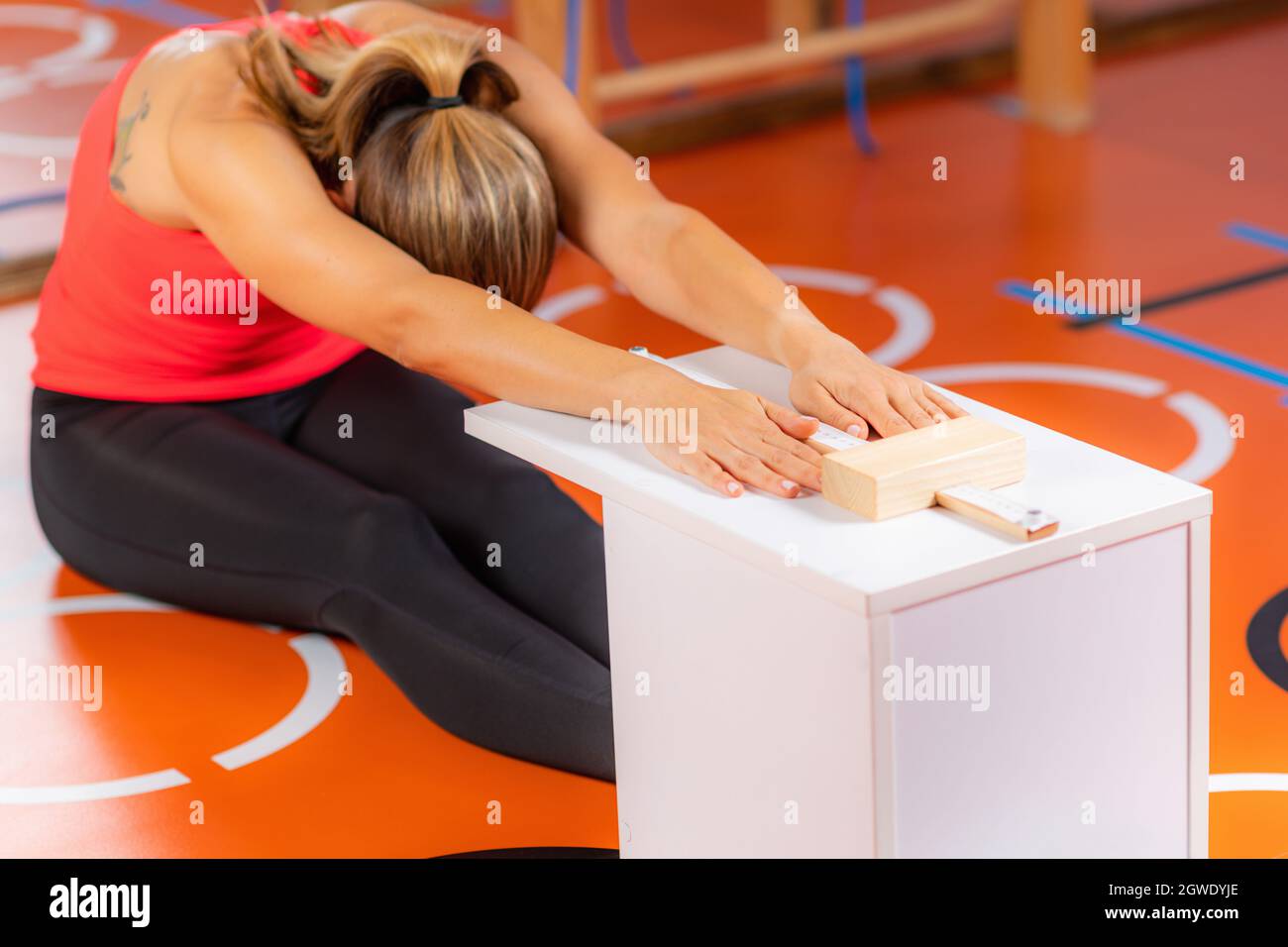 Mujer que se sienta y alcanza la prueba de flexibilidad Foto de stock