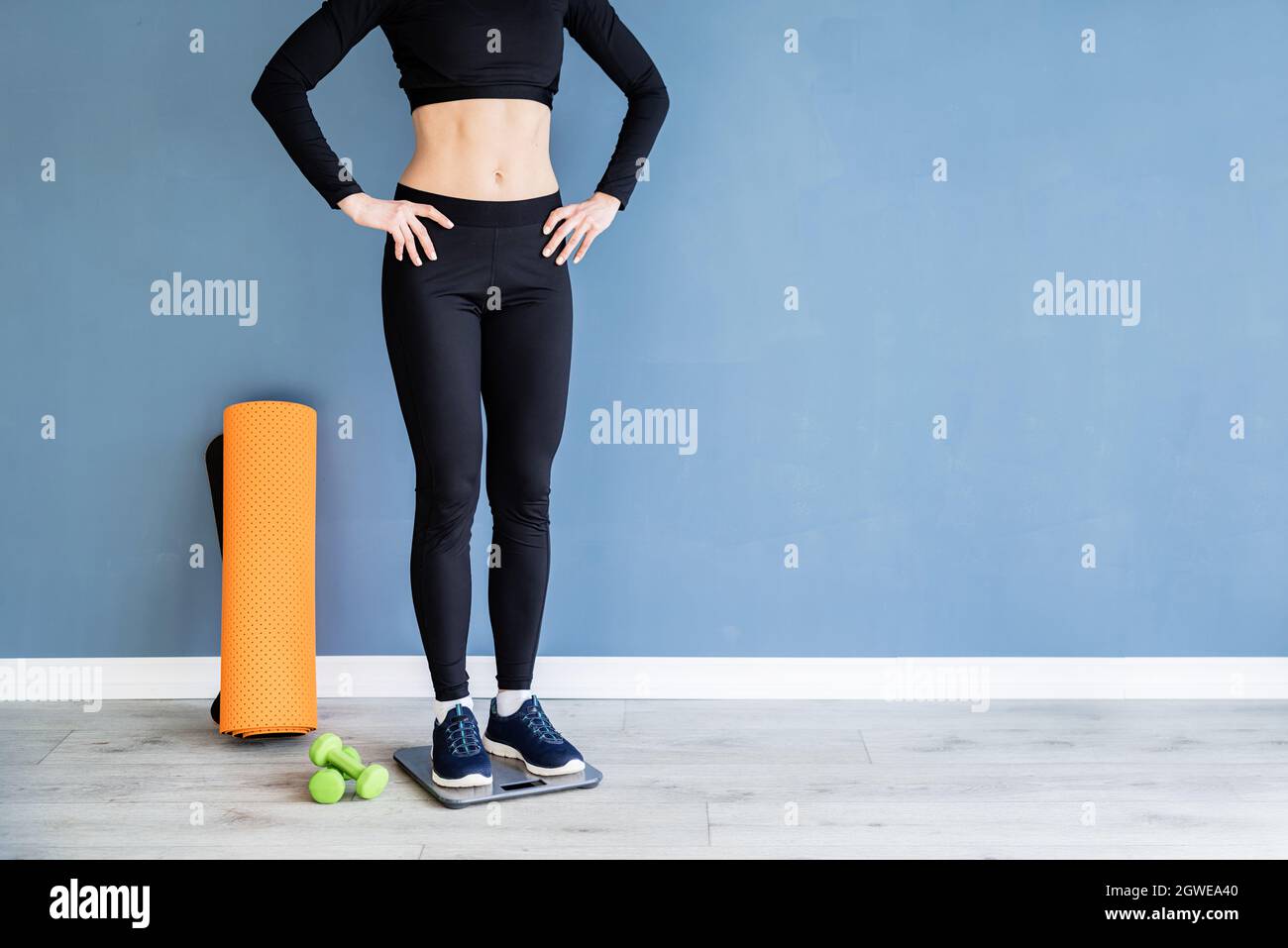 Dieta y pérdida de peso. Mujer en ropa deportiva negra de pie sobre  básculas Fotografía de stock - Alamy
