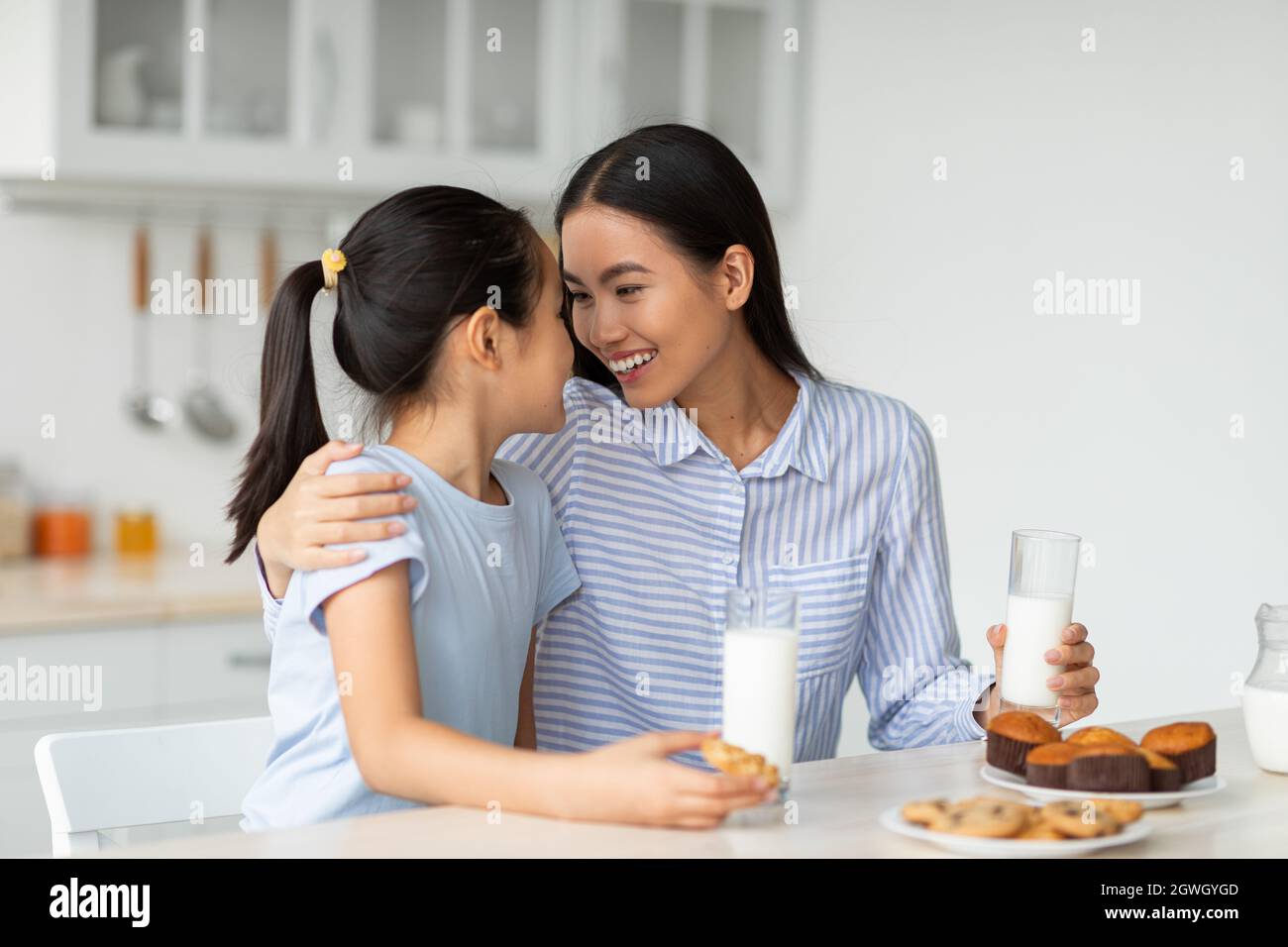 Feliz Amante De Asia Madre Y Pequeña Hija Comer Aperitivos En La Cocina Juntos Mamá Joven Y Su 