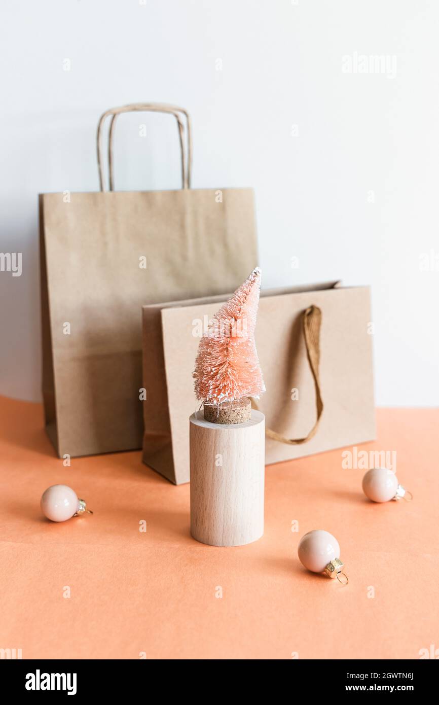 Árbol de Navidad de fibra de coco naranja sobre soporte de madera, bolsa de  regalo de papel Kraft sobre fondo blanco rosa Fotografía de stock - Alamy