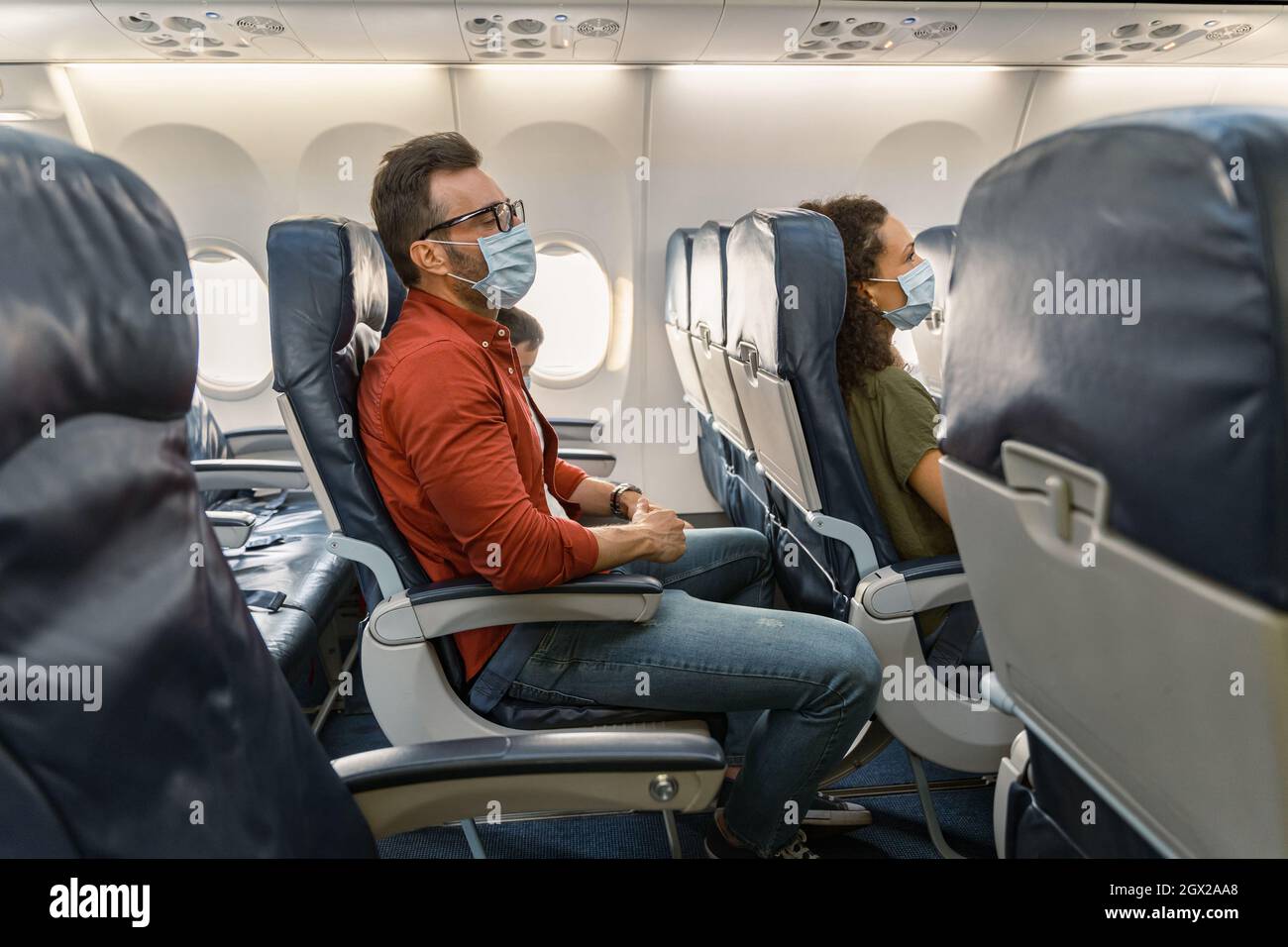 Pasajero masculino con gafas descansando en una silla durante un vuelo en un avión Foto de stock