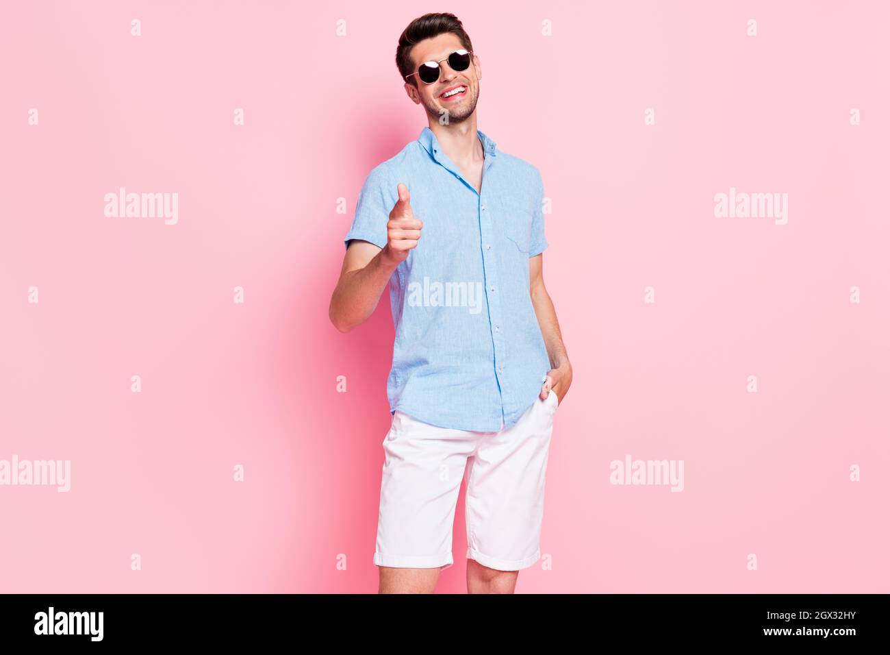 Foto retrato hombre sonriente con camisa azul cristal de sol apuntando con  el dedo hacia usted seleccionar aislado color rosa pastel fondo Fotografía  de stock - Alamy