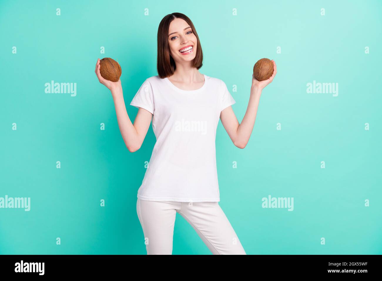Foto de divertido morena cabello joven dama sostener coco ropa camiseta  blanca aislado sobre fondo de color verde azulado Fotografía de stock -  Alamy