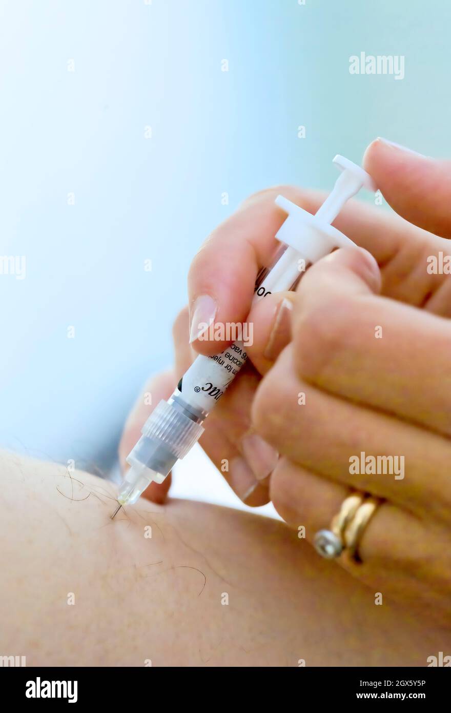 Paciente que recibe una vacuna contra la influenza, administrada por una aguja en la parte superior del brazo. Foto de stock