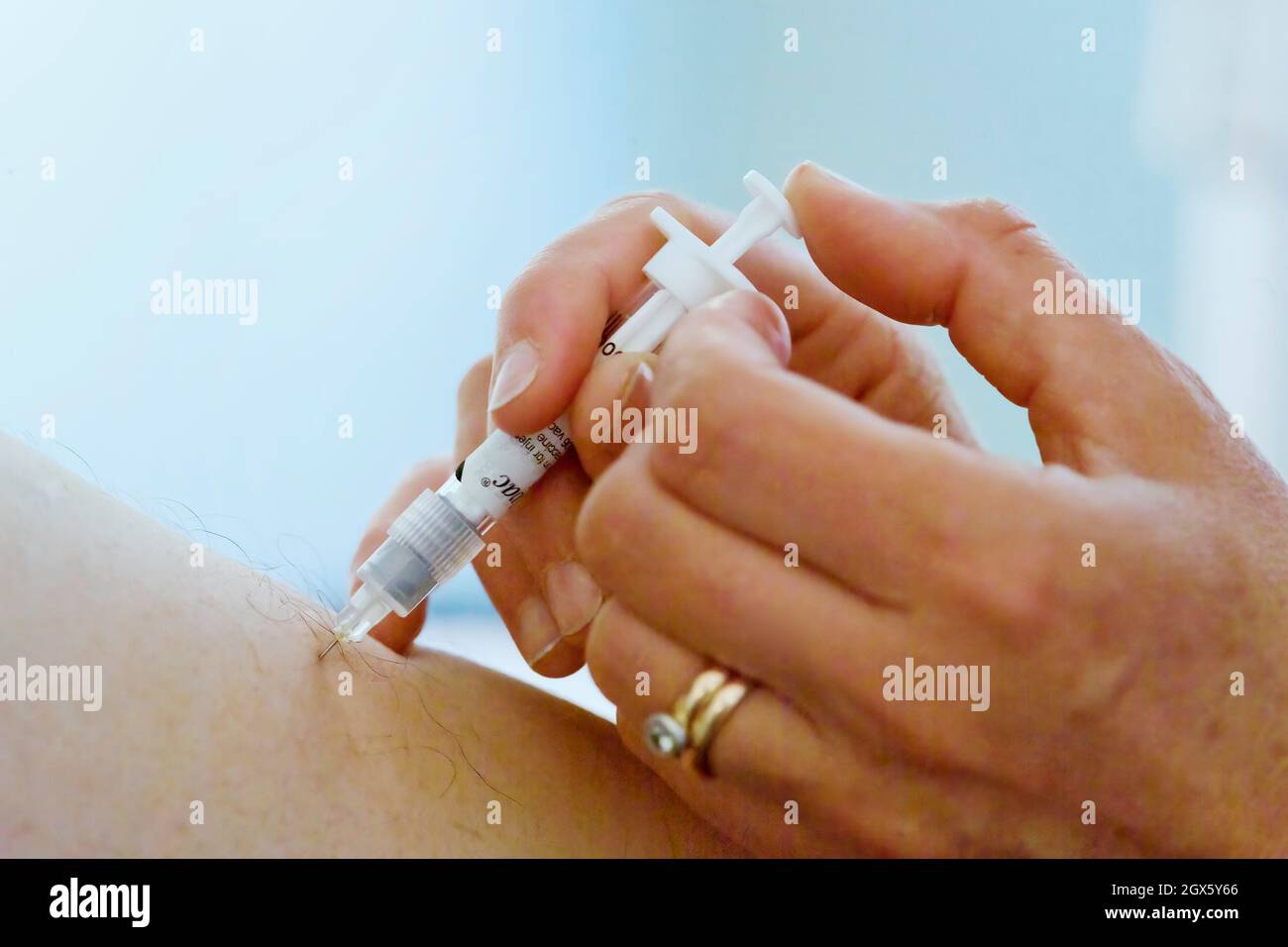Paciente que recibe una vacuna contra la influenza, administrada por una aguja en la parte superior del brazo. Foto de stock