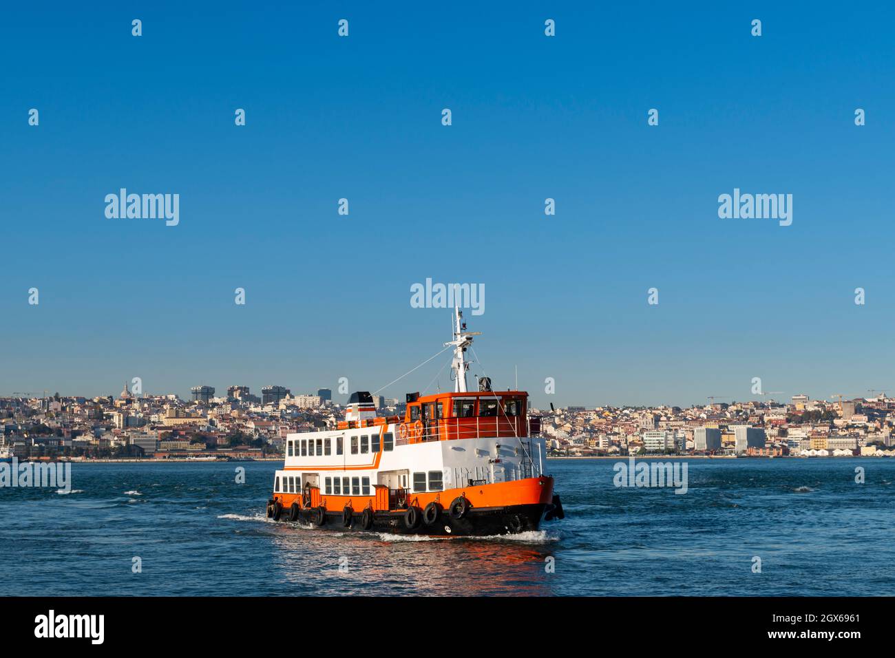 Un tradicional ferry de cacilheiro que cruza el río Tajo (Río Tejo) con la ciudad de Lisboa al fondo. Foto de stock