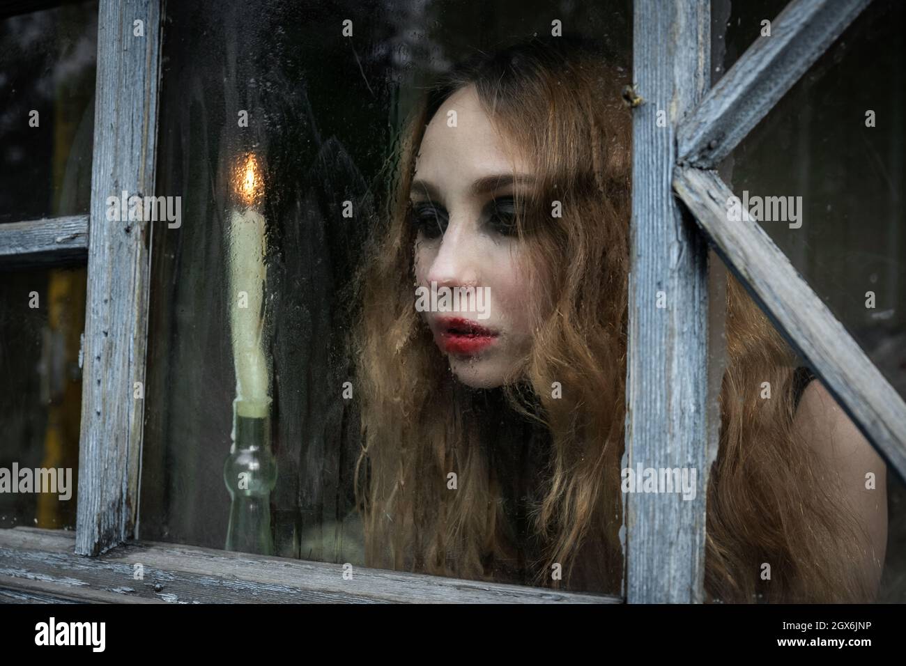 Hermosa chica joven triste mirando por la ventana con una vela, bueno para  la cubierta del libro Fotografía de stock - Alamy