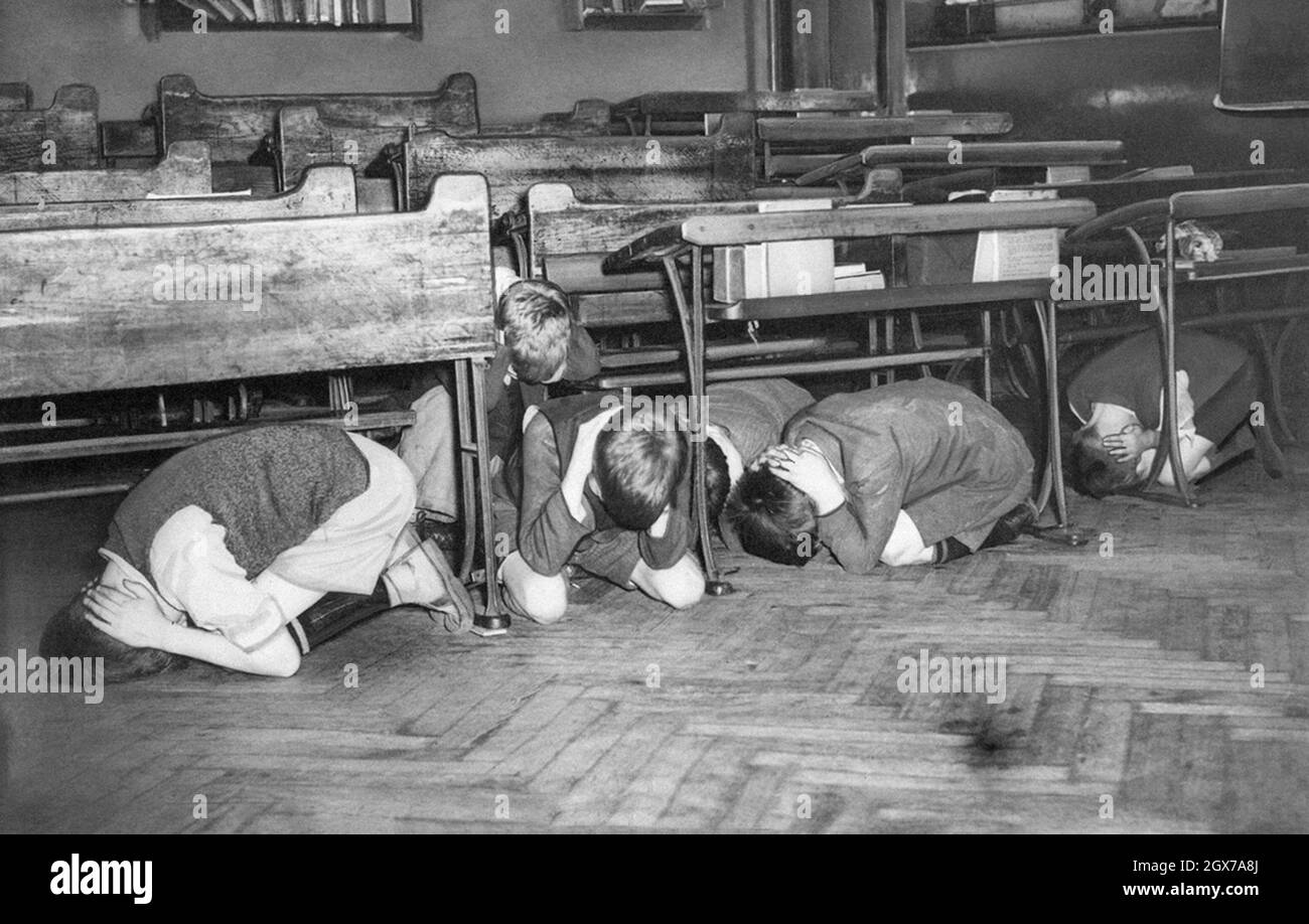 Estos escolares de Londres en un simulacro de ataque aéreo como precaución en caso de que una incursión aérea llegue demasiado rápido para darles la oportunidad de salir del edificio el 20 de julio de 1940. Se les dijo que fueran al medio de la habitación, lejos de las ventanas, y que sujetaran sus manos sobre la parte trasera de sus cuellos. Foto de stock