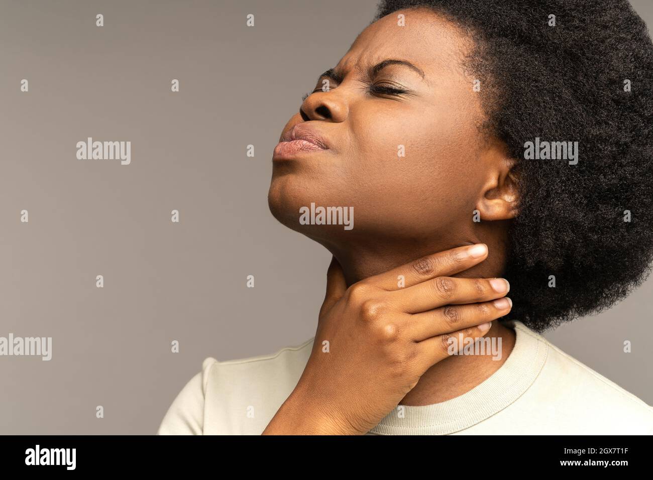 Una mujer africana enferma con dolor de garganta toca el cuello Sentir malestar, dolor al tragar sufrir de angina Foto de stock
