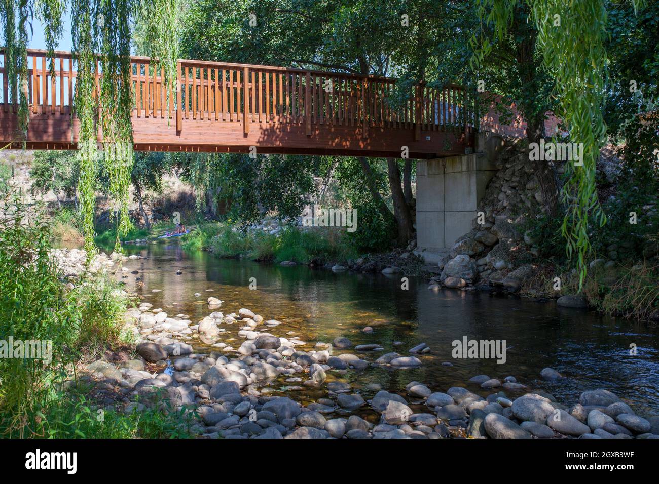Puente peatonal de madera en la zona recreativa del río Ambroz de Abadia, Cáceres, Extremadura, España. Foto de stock