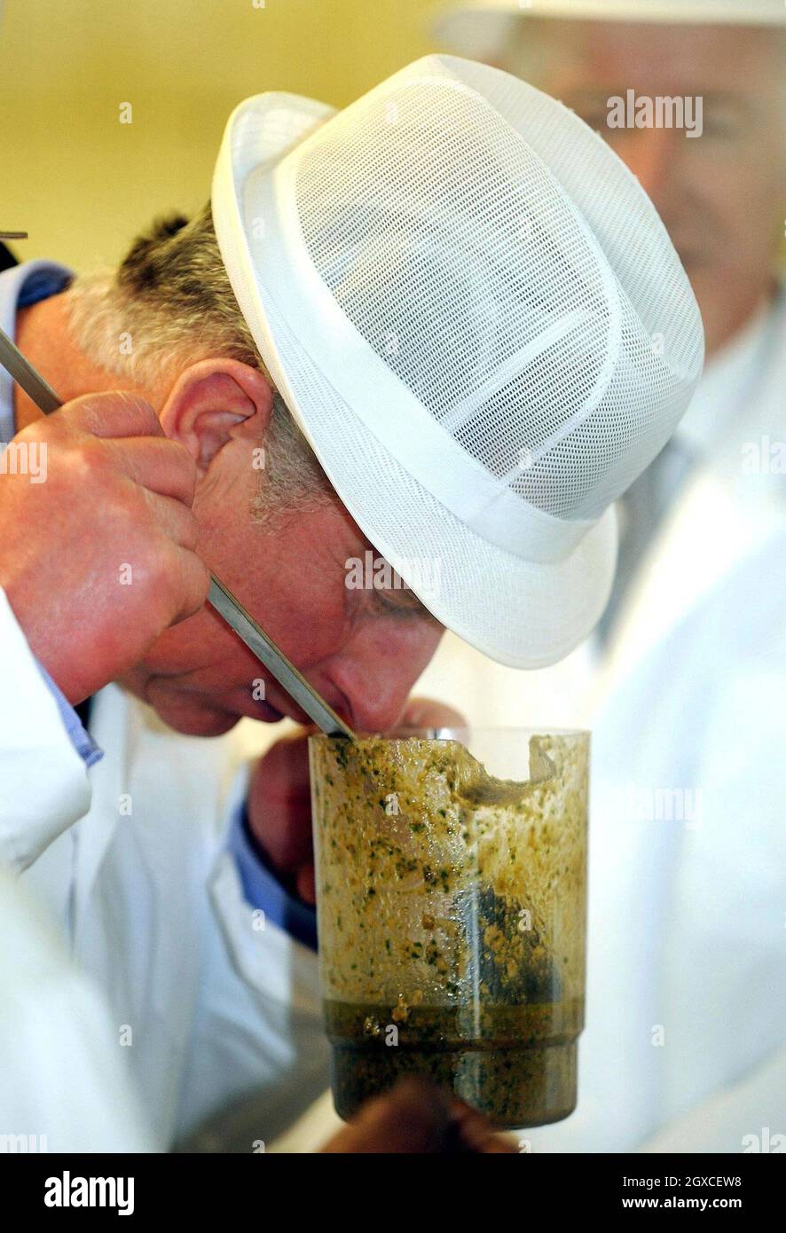 El Príncipe Carlos, Príncipe de Gales, lleva un sombrero y un abrigo  blancos mientras huele salsa de pesto durante una visita a las cocinas del  Hospital Royal Brompton en el oeste de
