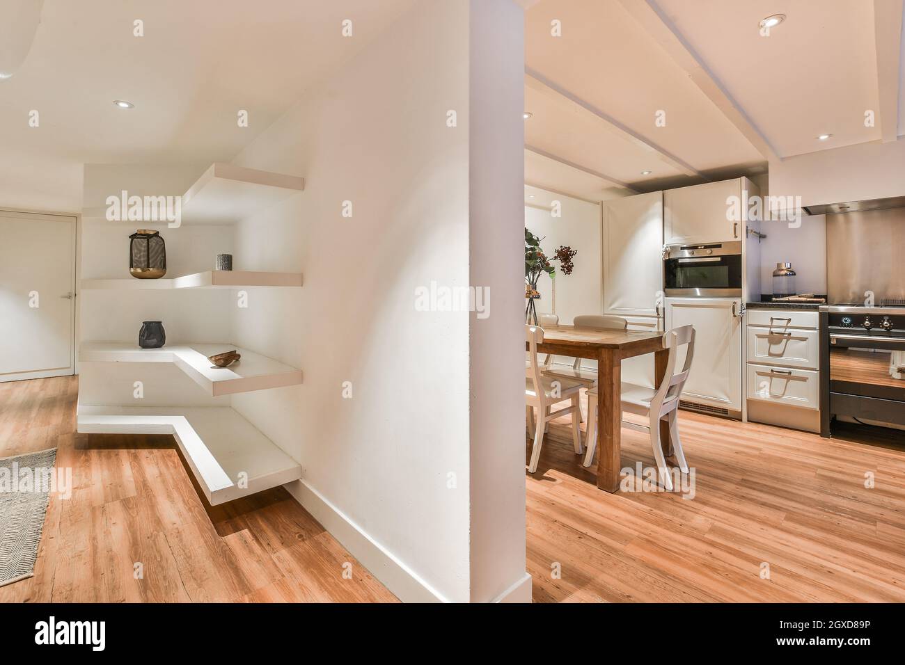 Interior de cocina moderna con mesa de comedor y sala de estar con estantes  separados por pared blanca en el piso Fotografía de stock - Alamy