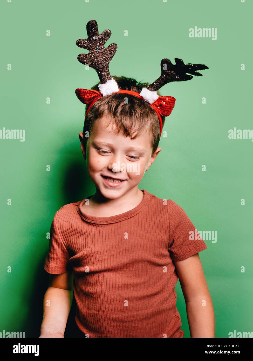 Chico sonriente con cuernos de reno diadema pie sobre fondo mirando hacia abajo Fotografía de stock - Alamy