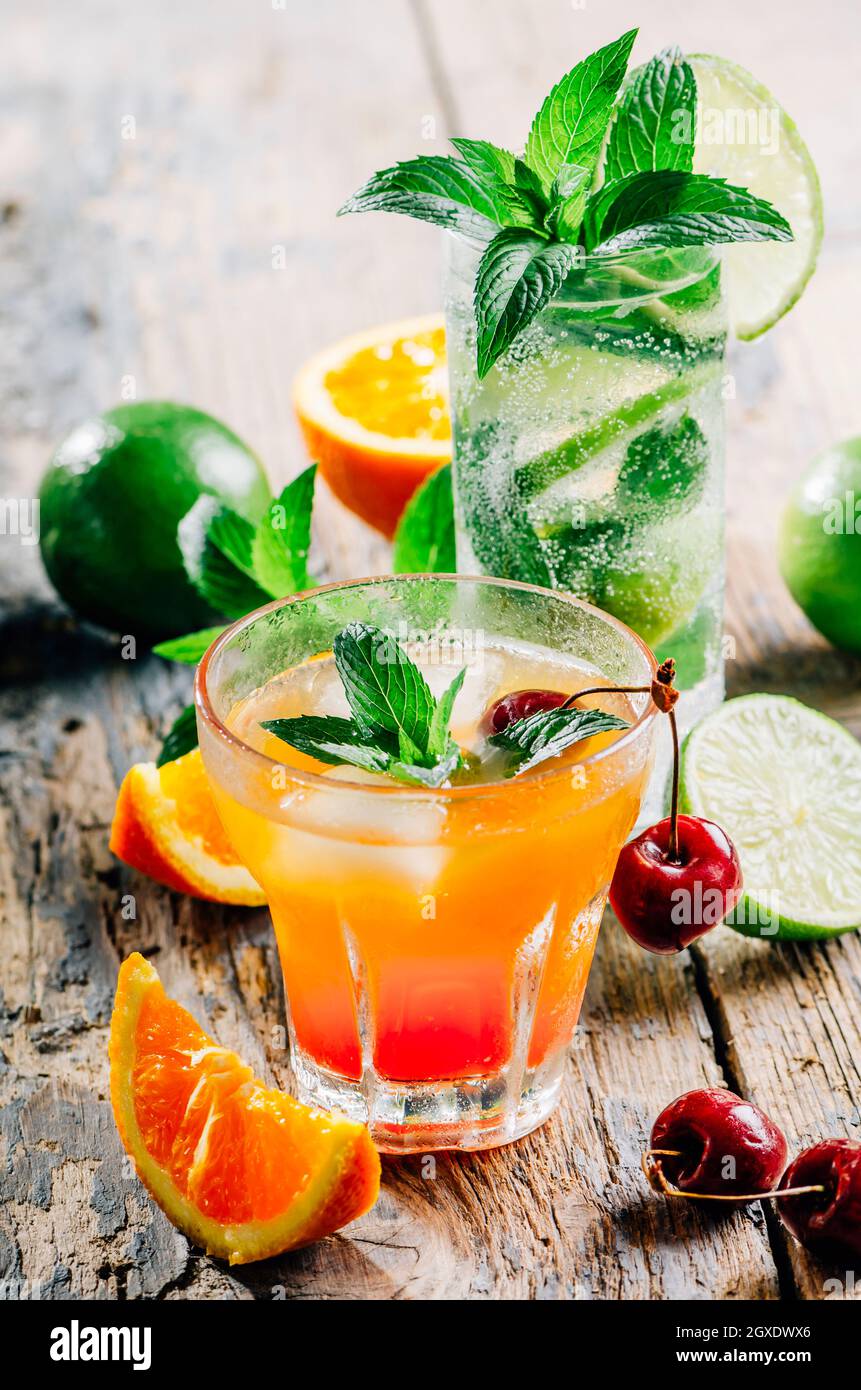 marcador empujoncito Imaginativo Varias bebidas de cóctel se mezclan con frutas y alcohol en una mesa de  madera de arriba. Bebida de jugo tropical con guarnición de naranja, lima,  cereza y menta Fotografía de stock -