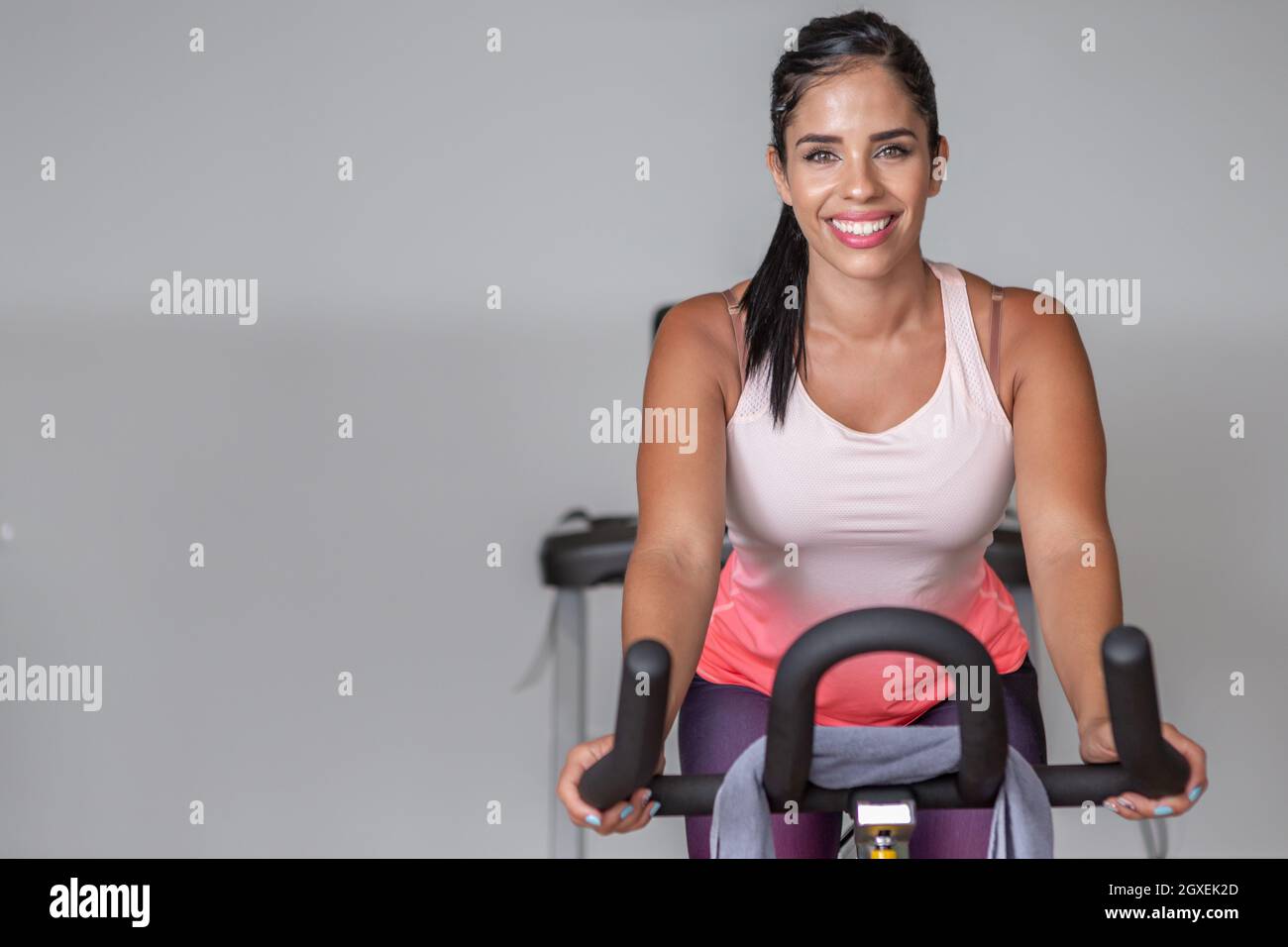 Vista frontal de una joven y sonriente mujer adulta mirando la cámara en ropa  deportiva haciendo ejercicio en bicicleta en el gimnasio con espacio para  copiar Fotografía de stock - Alamy