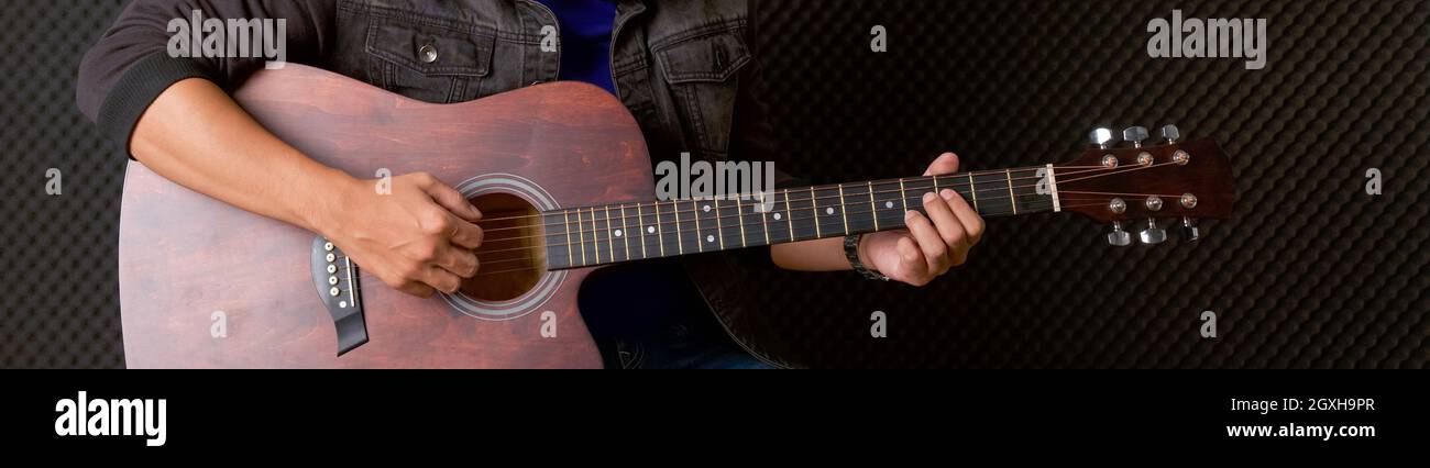 Mano del músico de primer plano tocando una guitarra acústica frente a  paredes de insonorización negra. Músico que produce música en un estudio de  grabación profesional Fotografía de stock - Alamy