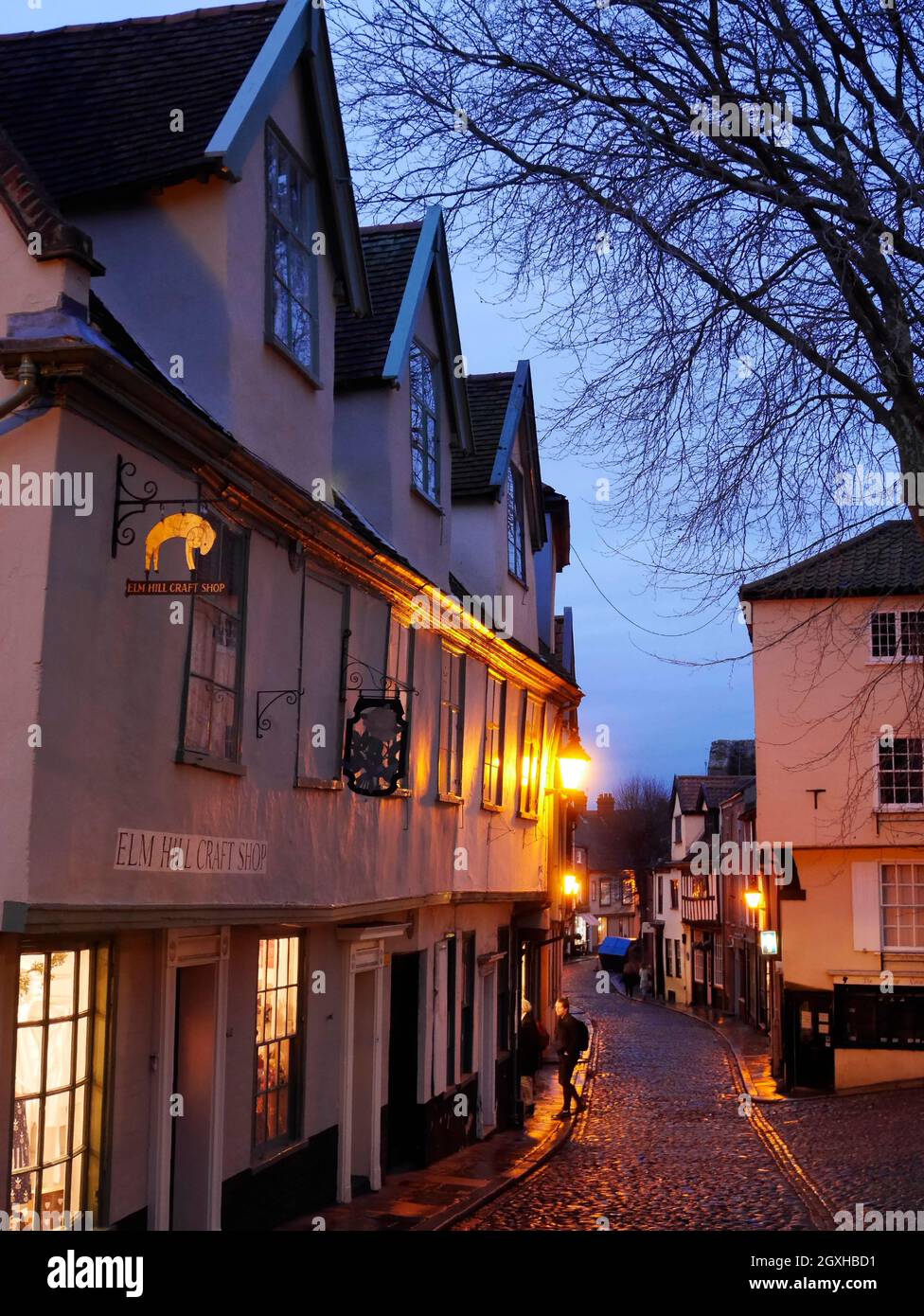 El histórico Elm Hill empedrado en Nightfall con sus linternas doradas y ventanas iluminadas, Norwich, Norfolk, Inglaterra, Reino Unido Foto de stock