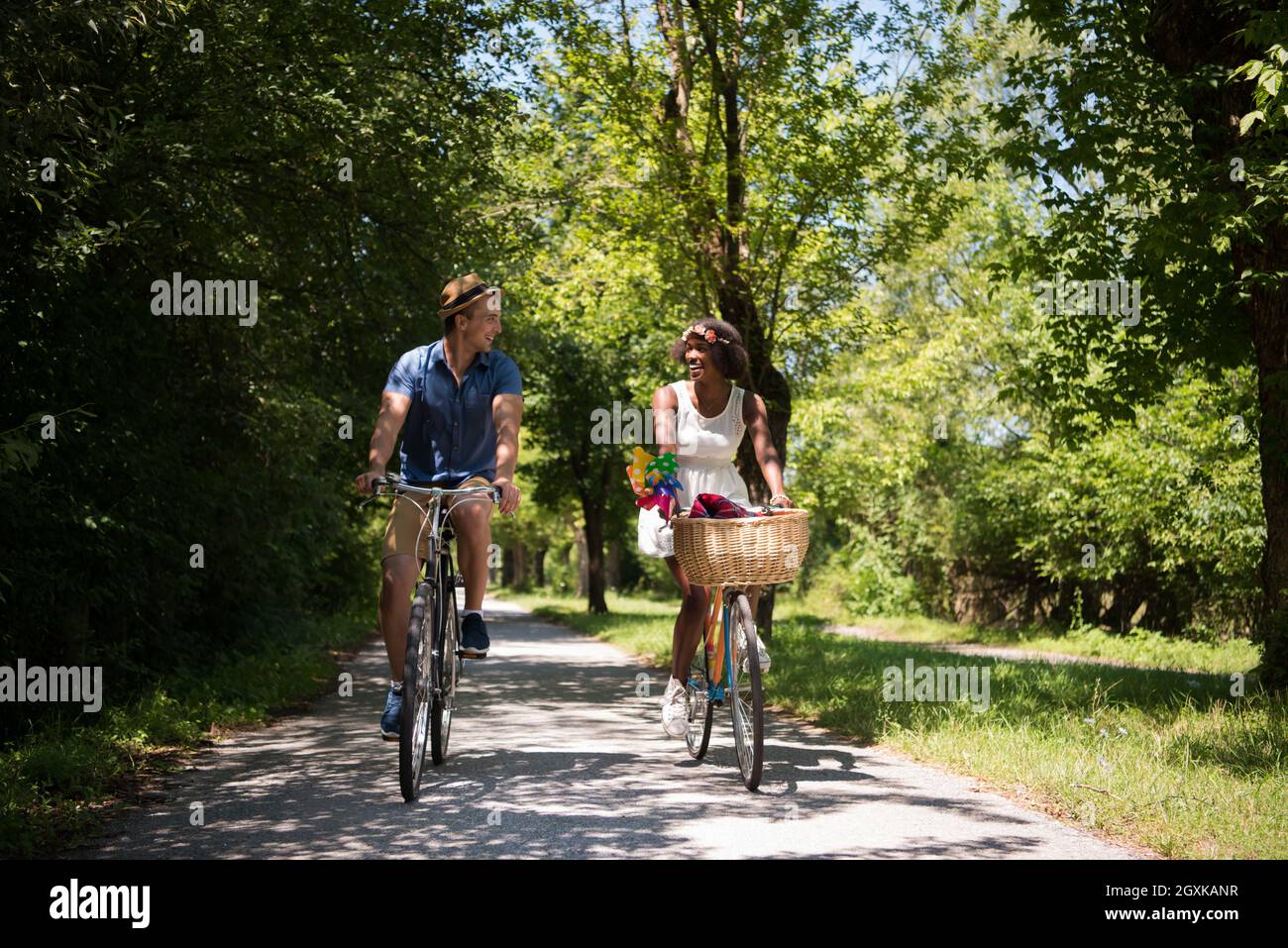 Un joven y una hermosa chica americana africana disfrutando de un paseo en  bicicleta en la naturaleza en un día soleado de verano Fotografía de stock  - Alamy