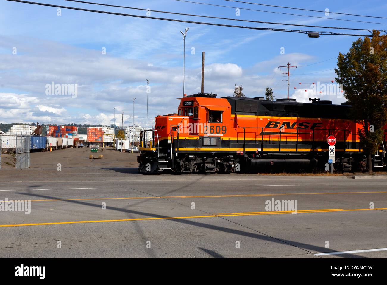 Una locomotora ferroviaria BNSF viaja a lo largo de W Marginal Way SW en el barrio Industrial District West de Seattle, Washington. Terminal 103 en el bac Foto de stock
