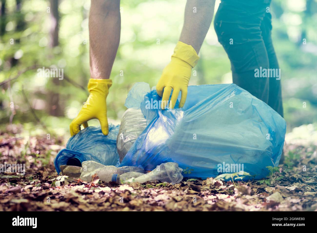 Mano recogiendo plástico de basura para limpiar los bosques o parques