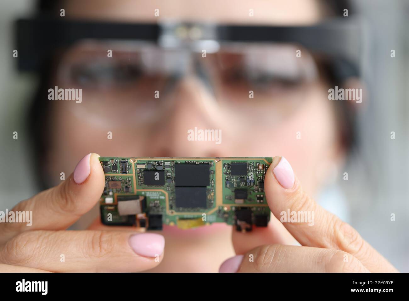 A través de la lente de aumento, el ingeniero mira el chip de la computadora Foto de stock