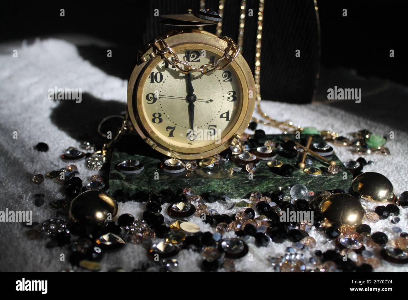 hermoso reloj de bronce antiguo en la mesa verde mabel decorado piedras brillantes Foto de stock