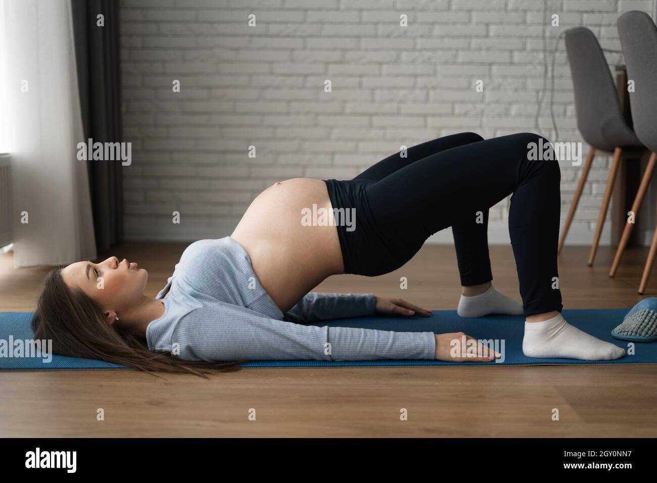 Hermosa mujer embarazada haciendo ejercicios en casa. Se acuesta en su espalda y se levanta. Foto de stock