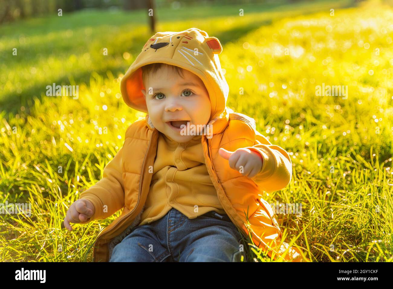 Retrato emotivo de un niño sonriente. Feliz niño caucásico con chaqueta amarilla fondo verde claro al aire al atardecer Fotografía de stock - Alamy