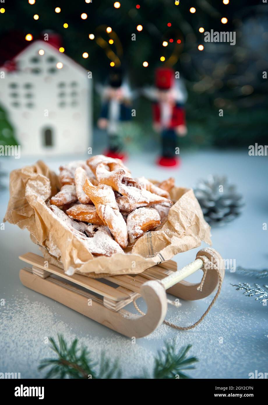 Decoración navideña con trineo de madera antiguo. Galletas caseras recién horneadas en la forma de un árbol de Navidad con decoraciones coloridas o. Foto de stock