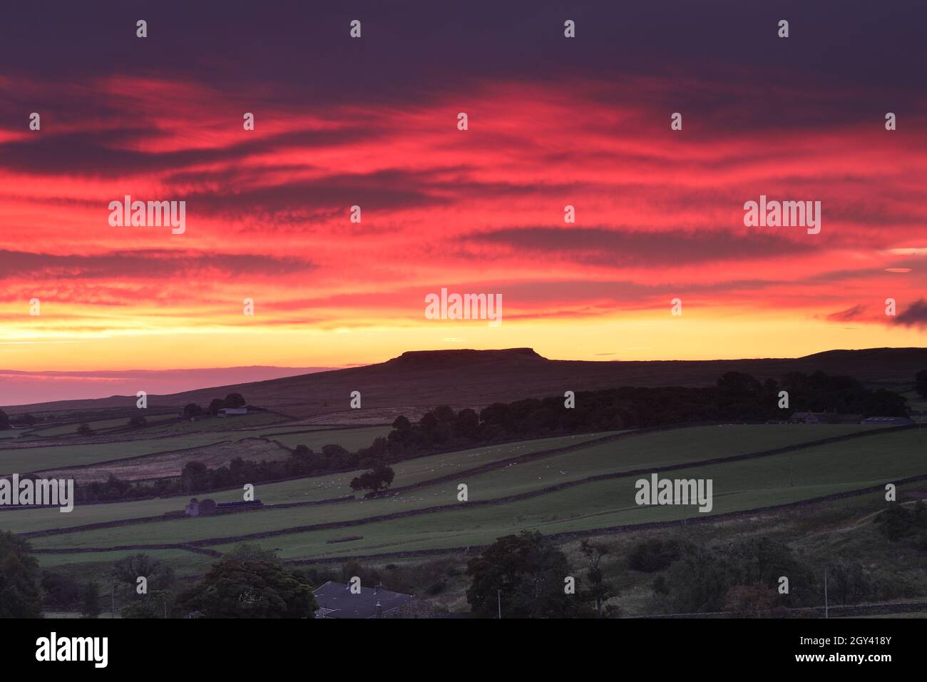 Un colorido cielo al amanecer sobre la colina cubierta de la superficie plana de Goldsborough visto desde Balderhead, Baldersdale, Teesdale, Condado de Durham, Reino Unido Foto de stock