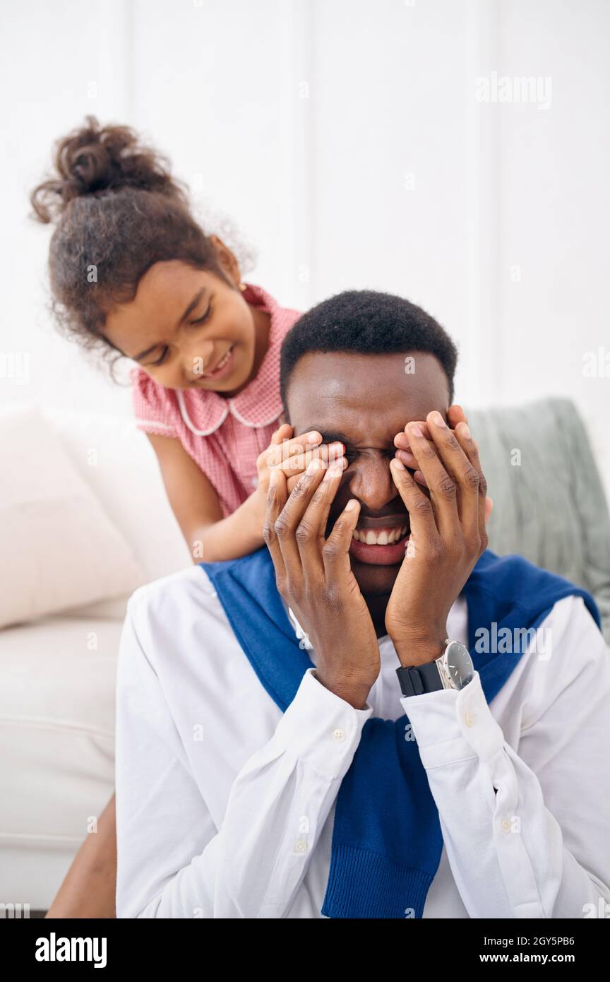 El padre sonriente y la hija pequeña se posan en la sala de estar. Papá y  niña de sexo femenino en su casa juntos, feliz relación Fotografía de stock  - Alamy