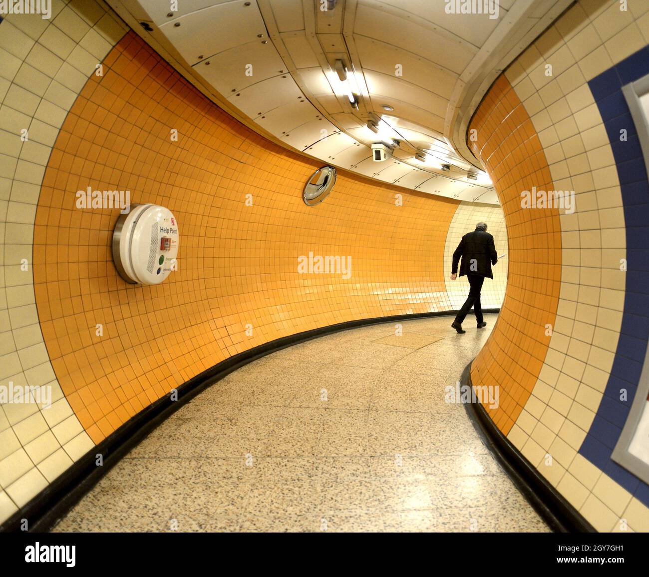 Londres, Inglaterra, Reino Unido. Hombre caminando a través de un túnel en una estación de metro Foto de stock