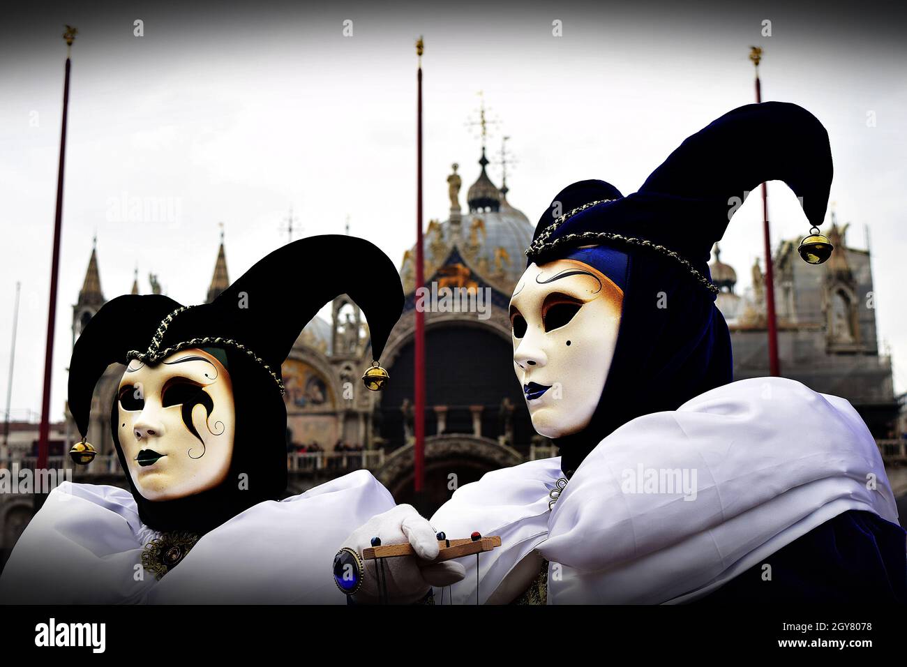 VENECIA, ITALIA - 09 de febrero de 2016: Dos joker disfrazaron máscaras en el Carnaval de Venecia con la Basílica de San Marcos en el fondo. Trajes a juego CO Foto de stock