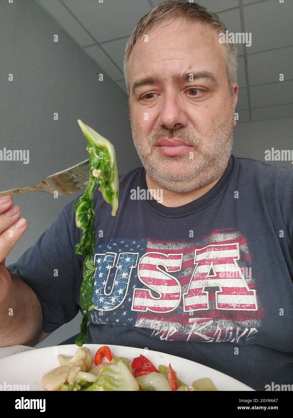El hombre gordo disgustado por las verduras frondosas Foto de stock