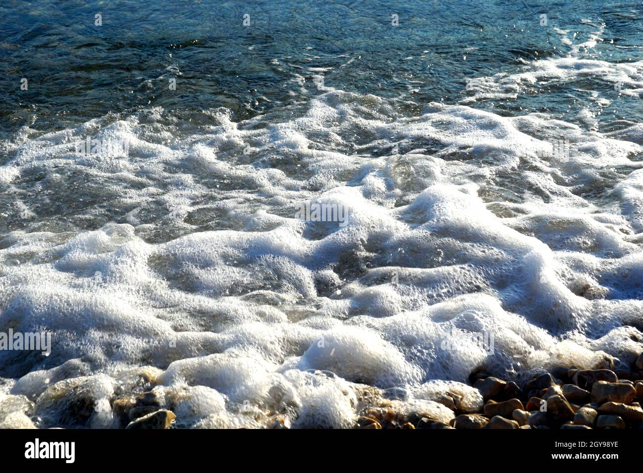 Agitación de agua de mar con espuma de mar blanca en la superficie azul del mar Foto de stock
