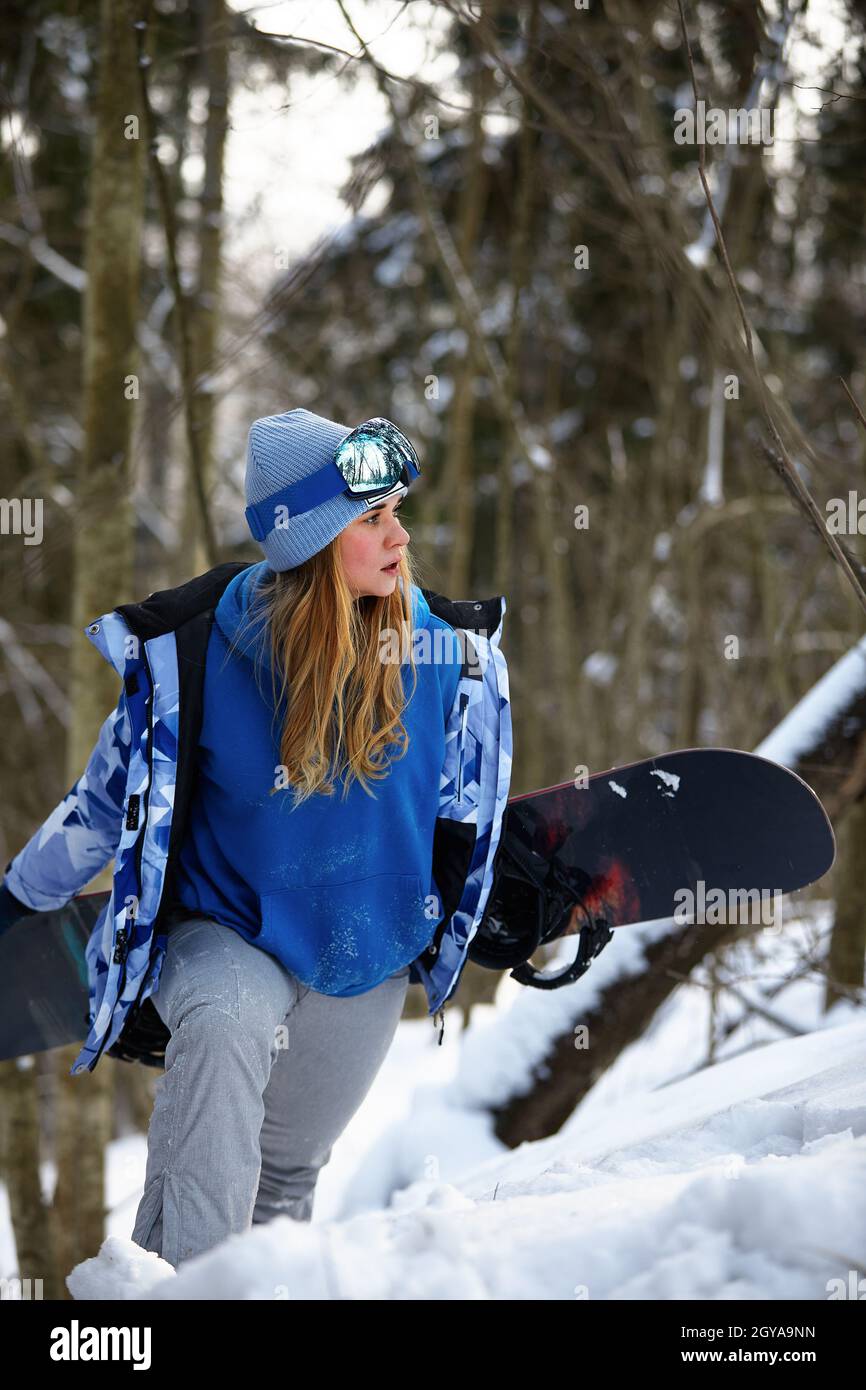 imagen con un retrato de una snowboarder mujer con casco con un reflejo brillante en las gafas sobre el fondo de la montaña de nieve alta. Foto de stock