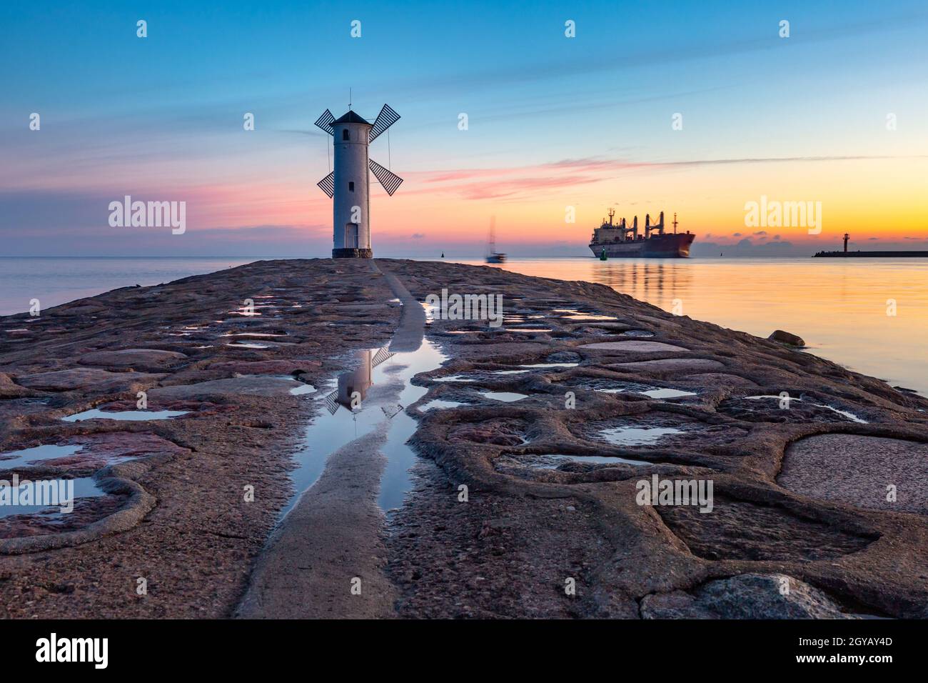 Mar Báltico y Stawa Mlyny, faro de navegación en forma de molino de viento al atardecer, símbolo oficial de Swinoujscie, Polonia Foto de stock