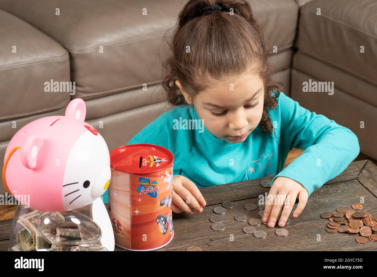 Niña de cinco años en casa, clasificando y contando monedas Foto de stock
