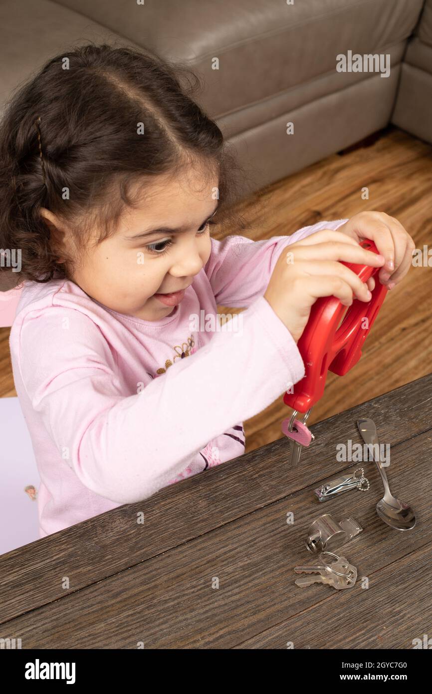 Niña de tres años jugando con objetos de imán y metal Foto de stock