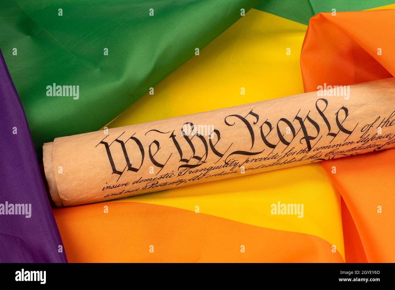La constitución de Estados Unidos, insinuando leyes y libertad, descansa sobre una porción de una bandera arcoiris, destacando la igualdad de derechos entre grupos con diferentes sexu Foto de stock