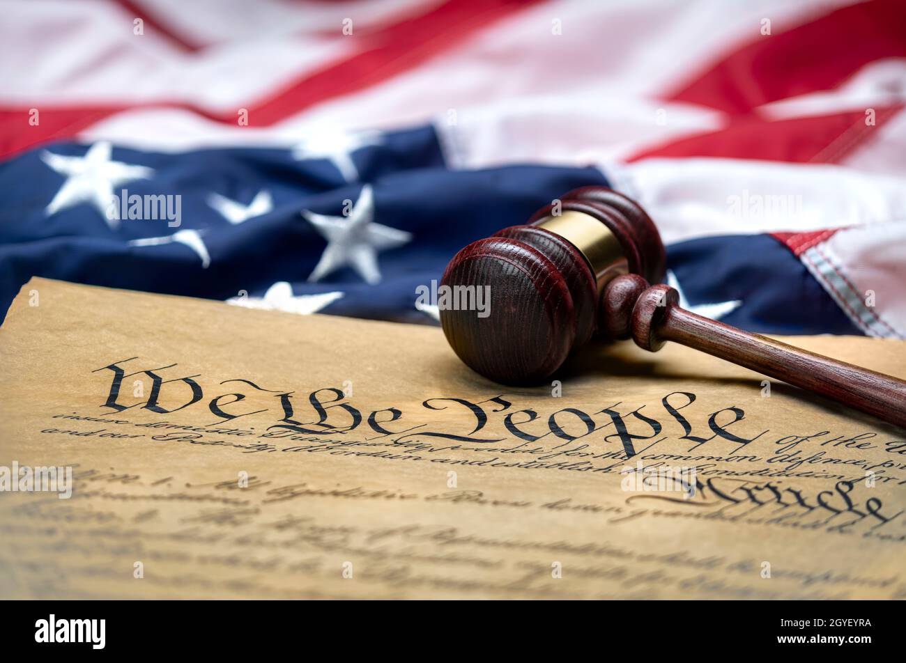 La bandera estadounidense se alzó alrededor del bloque de gavel de un juez y de la Constitución de los Estados Unidos para su uso como símbolo de leyes, libertad y separación del gobierno Foto de stock