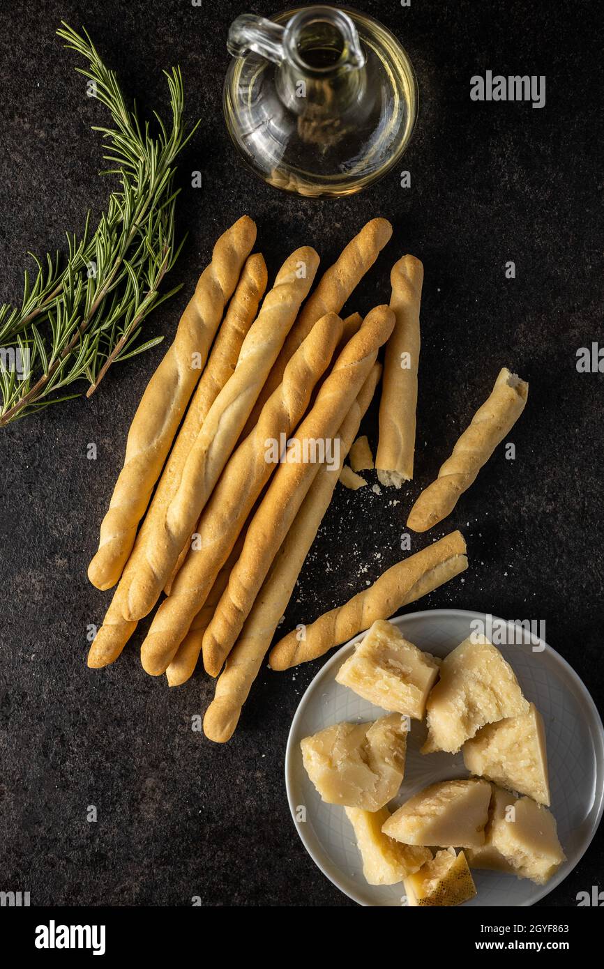 Palos de grissini y queso parmesano. Comida tradicional italiana sobre mesa negra. Vista superior. Foto de stock