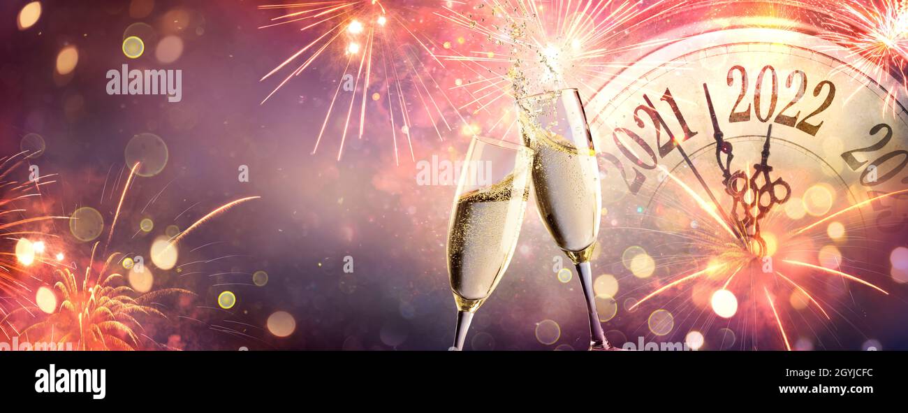 Celebración del Año Nuevo 2022 - Cuenta regresiva y tostado con champán y fuegos artificiales sobre fondo abstracto desfocado Foto de stock